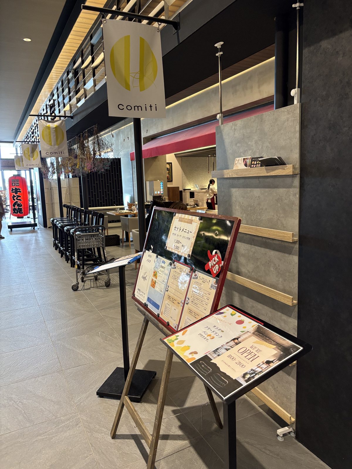 comitiの白いのれんとメニュースタンドがある店頭