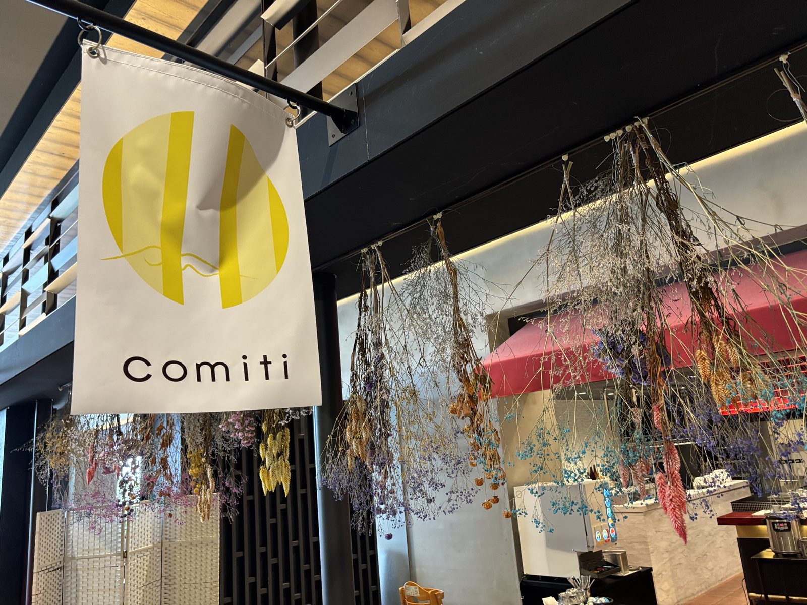 白いcomitiののれんとカラフルなドライフラワーが彩るオープンキッチン
