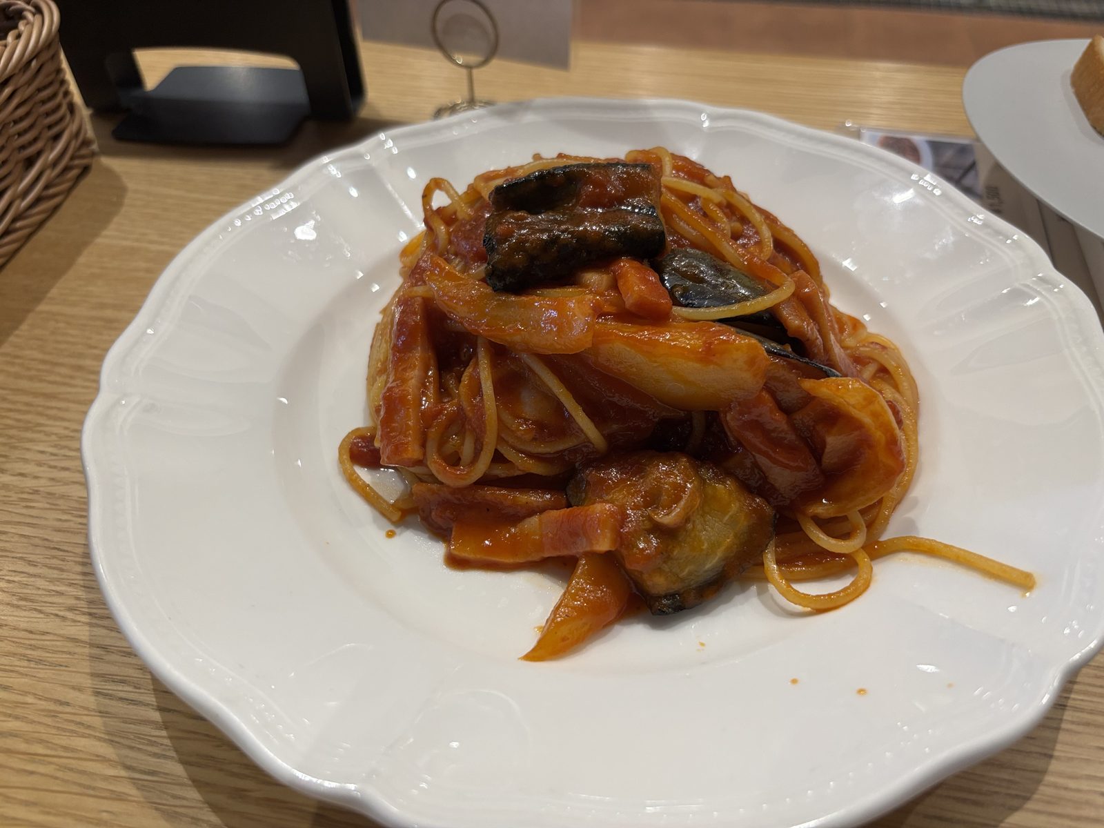 花形の白い皿に盛り付けたナスとベーコンのポモドーロパスタ