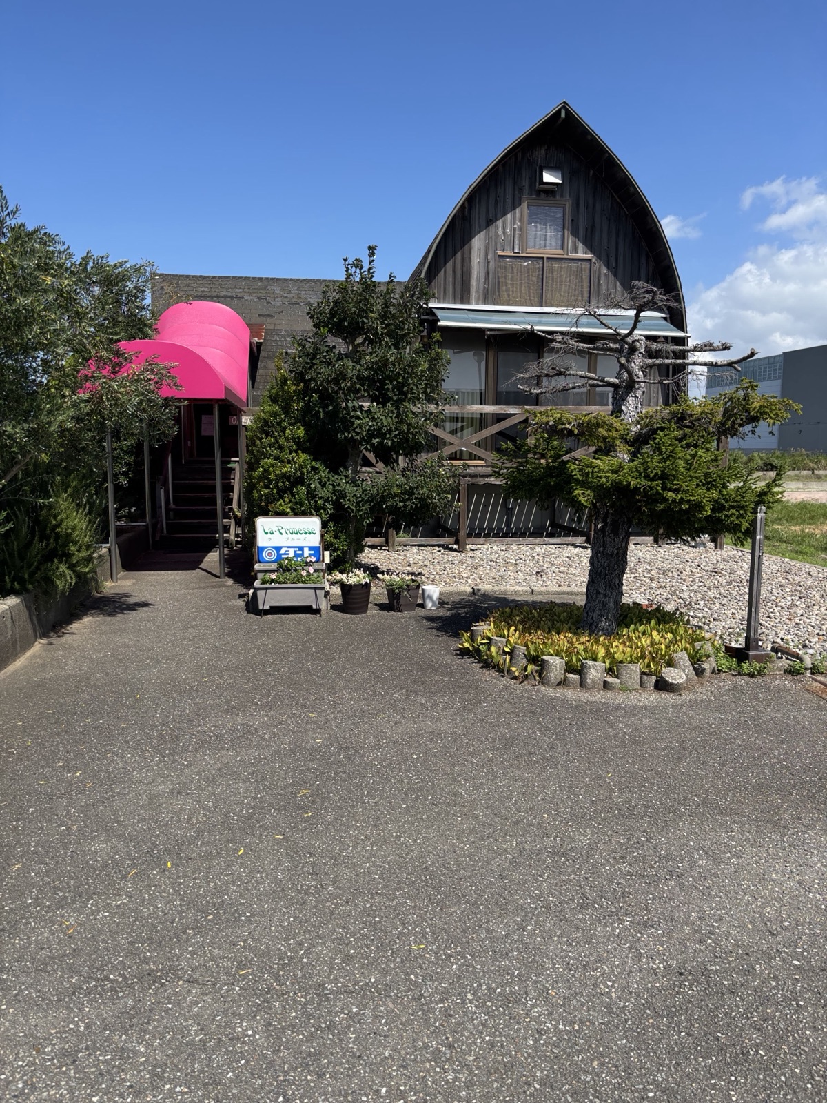 三角屋根の建物とピンクの日除け